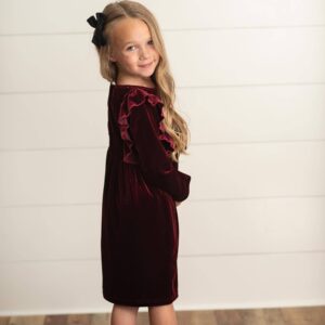 Girl in maroon dress with long hair and bow.