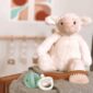 Plush lamb with pastel baby toys and brush.