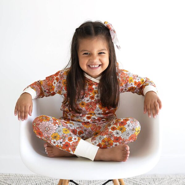 gigi and max louisa hoodie set Child smiling in floral pajamas on white chair.