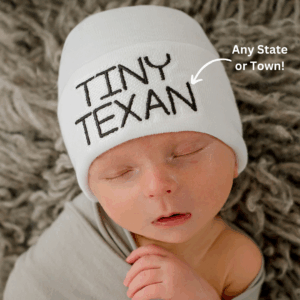 Baby wearing 'Tiny Texan' beanie, customizable location.