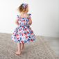 Child wearing butterfly patterned dress indoors.