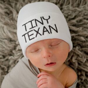 Sleeping baby in hat labeled 'Tiny Texan'.