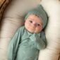 Baby in green outfit lying in basket