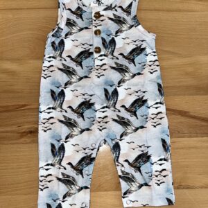 Duck-patterned baby romper on wooden surface.