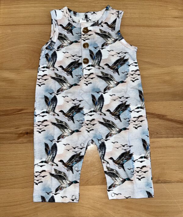 Duck-patterned baby romper on wooden surface.