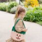 Child with pumpkin-themed bag in garden