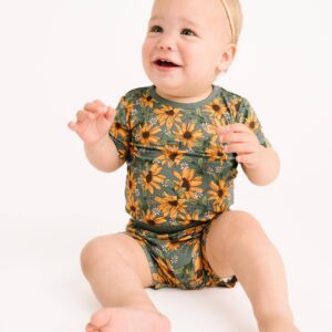 Smiling baby in floral onesie with headband.