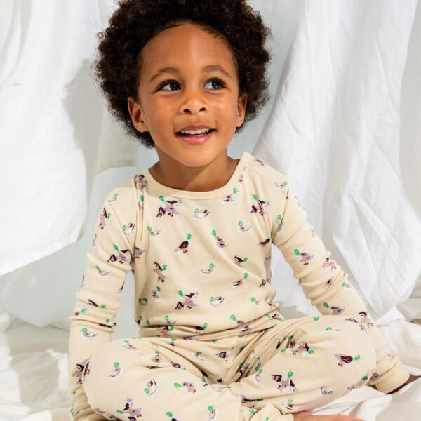 Smiling child wearing duck-patterned pajamas.