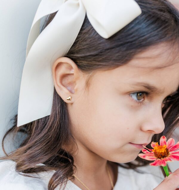 cherished moments kids 14k gold puff heart earrings Young girl with bow, heart earring, smelling flower.