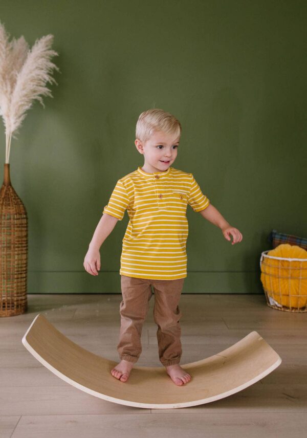 ollie jay alex tee in mustard stripe Child balancing on wooden board indoors