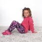 Smiling child in pink sweater and floral leggings.
