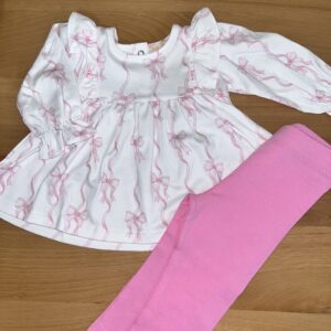 Pink leggings with white dress on wooden surface.