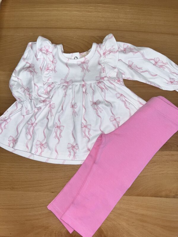 Pink leggings with white dress on wooden surface.