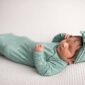Newborn baby in green outfit sleeping peacefully