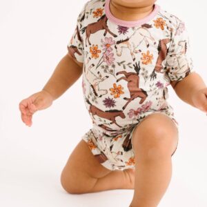 Baby in floral horse-patterned outfit crawling