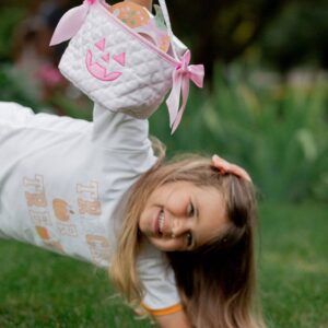 Girl holding Halloween basket upside down on grass