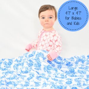 Baby holding large floral patterned blanket.