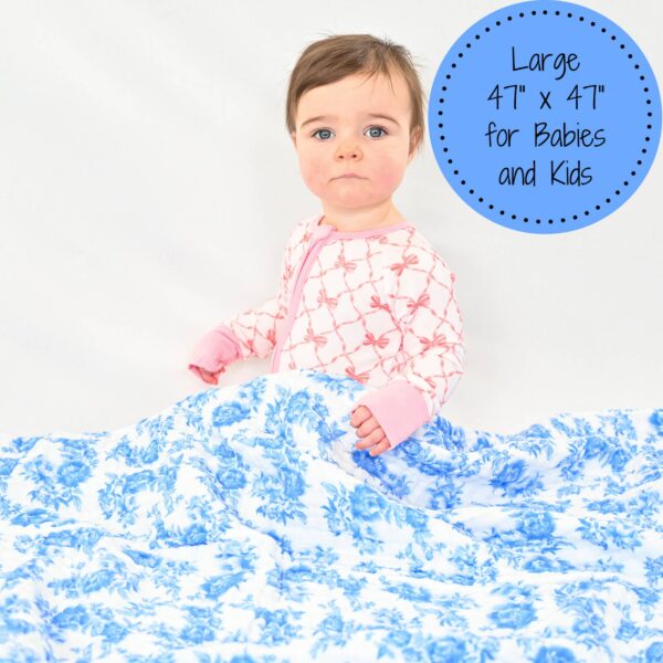 lollybanks a peony for your thoughts baby toddler muslin quilt Baby holding large floral patterned blanket.