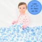 Baby holding large floral patterned blanket.