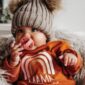 Baby in knit hat with pacifier, rainbow outfit.