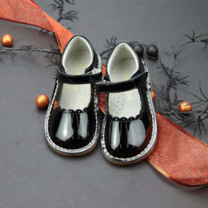 Black patent Mary Jane shoes with decorative background.