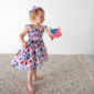 Child holding American flag in patriotic dress.