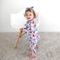 Baby in patterned outfit and headband near chair