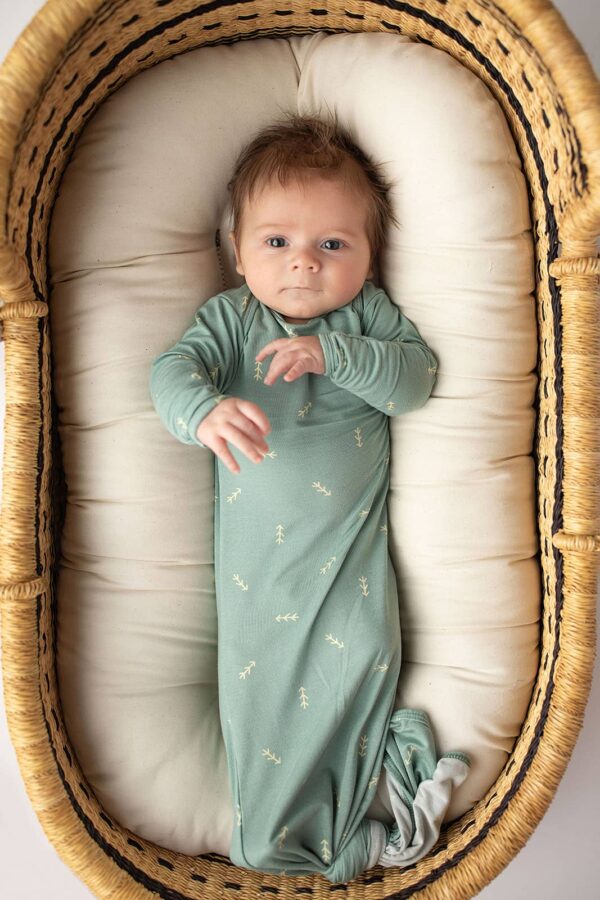 three little tots arrow print knotted newborn baby gown pajamas Baby in a cozy basket, wearing green onesie.