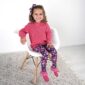 Smiling child in pink sweater and floral pants.