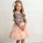 Young girl in floral dress, smiling indoors.