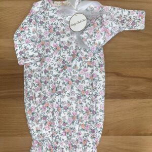 Floral baby onesie with gift tag on wood background.