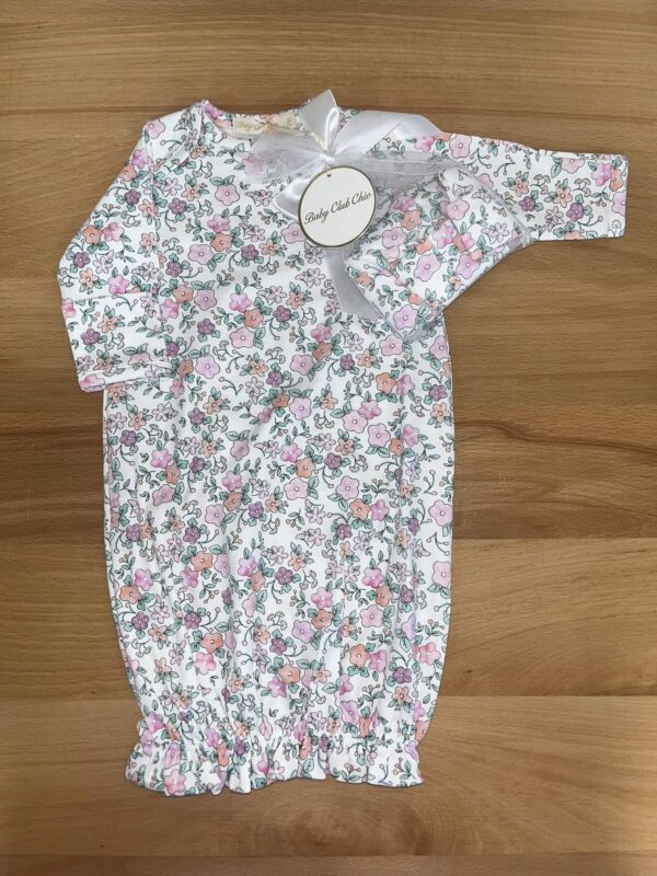 Floral baby onesie with gift tag on wood background.