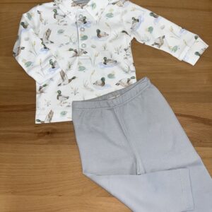Duck-patterned shirt with gray pants on table.