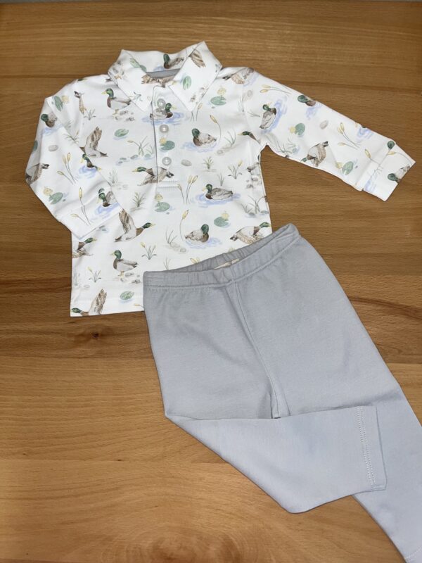 Duck-patterned shirt with gray pants on table.