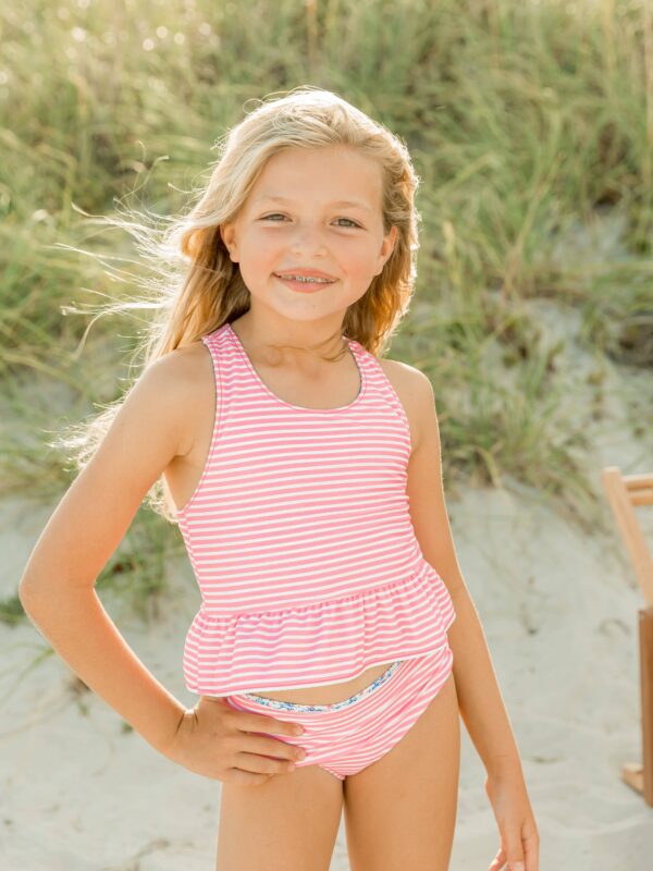 rufflebutts cottage tea time reversible peplum tankini Girl smiling at the beach in striped swimsuit.