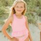 Girl smiling at the beach in striped swimsuit.