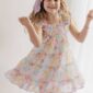 Girl wearing colorful dress and smiling joyfully.