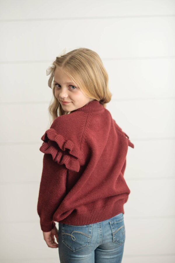 Girl in red sweater with ruffled sleeves.