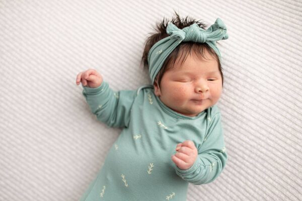 three little tots arrow print knotted newborn baby gown pajamas Sleeping newborn in green outfit and headband.