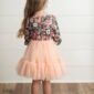 Young girl in floral top and peach tutu dress.