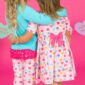Two kids hugging in heart-patterned clothes.
