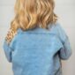 Blonde child wearing denim jacket from behind.