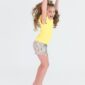 Child jumping in yellow shirt and floral shorts