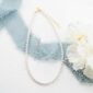 Elegant pearl necklace with blue ribbon and flowers.