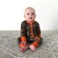 Baby wearing camouflage pajamas sitting on carpet