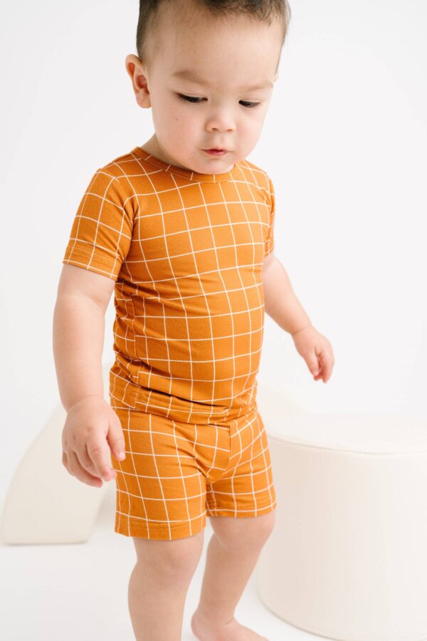 little one shop rust checks bamboo shorts set Child in orange checkered outfit on white background.
