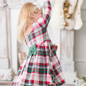Girl in plaid dress spins in festive living room.