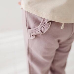 Child wearing pants with ruffled pocket detail.
