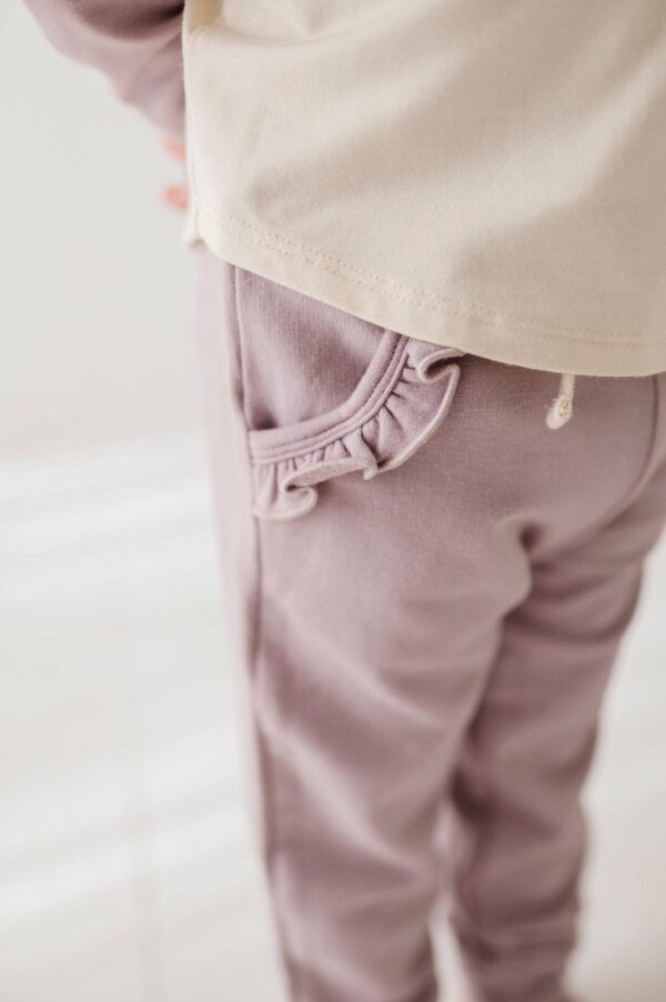 Child wearing pants with ruffled pocket detail.