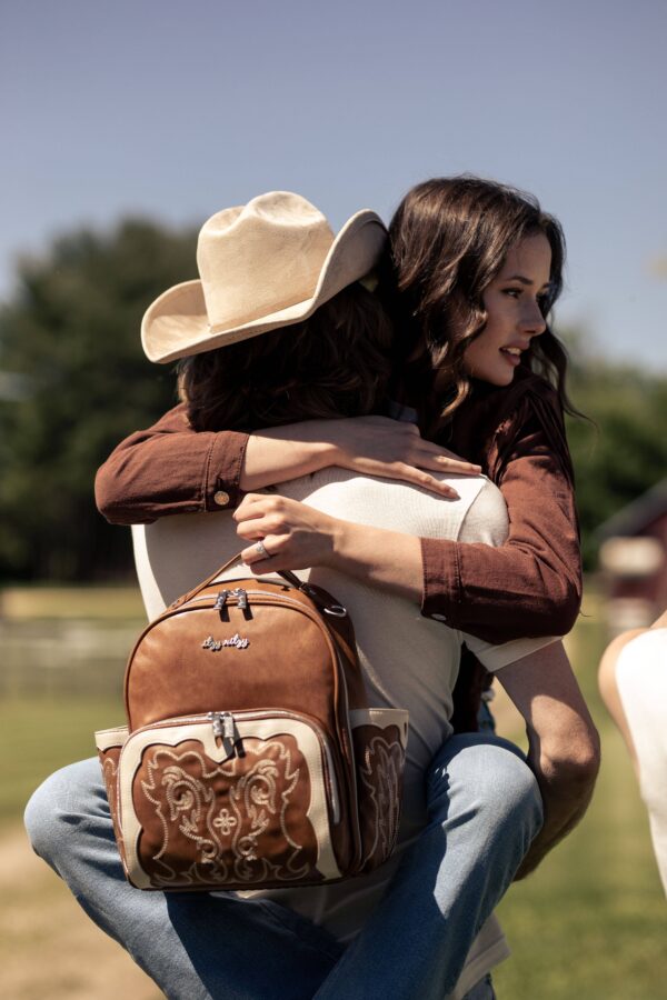 itzy ritzy nash mini plus™ backpack diaper bag Couple hugging outdoors with leather backpack.